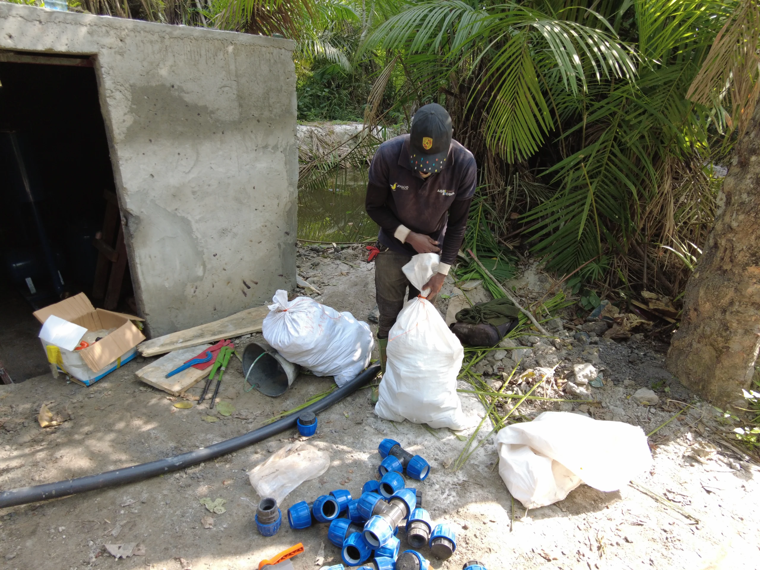 Technicien JOGOO Agriculture préparant des raccords près d'une cuve en béton sur un chantier d'eau